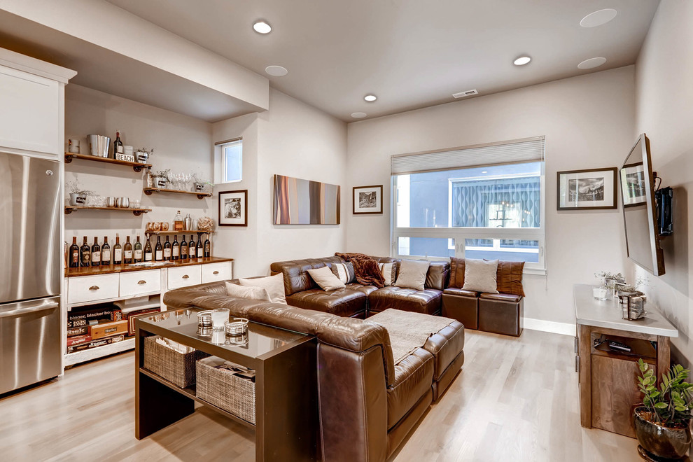 Photo of a mid-sized modern open concept living room in Denver with a home bar, grey walls, a wall-mounted tv, light hardwood floors and brown floor.