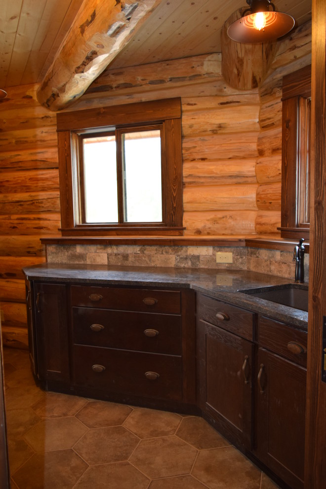 Example of a mountain style u-shaped dark wood floor eat-in kitchen design with a farmhouse sink, raised-panel cabinets, granite countertops, beige backsplash, stone tile backsplash, stainless steel appliances, an island and dark wood cabinets