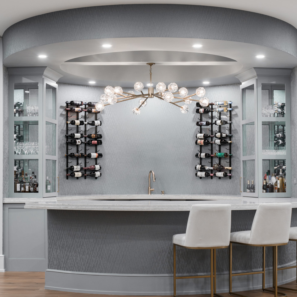 Design ideas for an expansive modern galley seated home bar in Chicago with an integrated sink, glass-front cabinets, grey cabinets, light hardwood floors, beige floor and grey benchtop.
