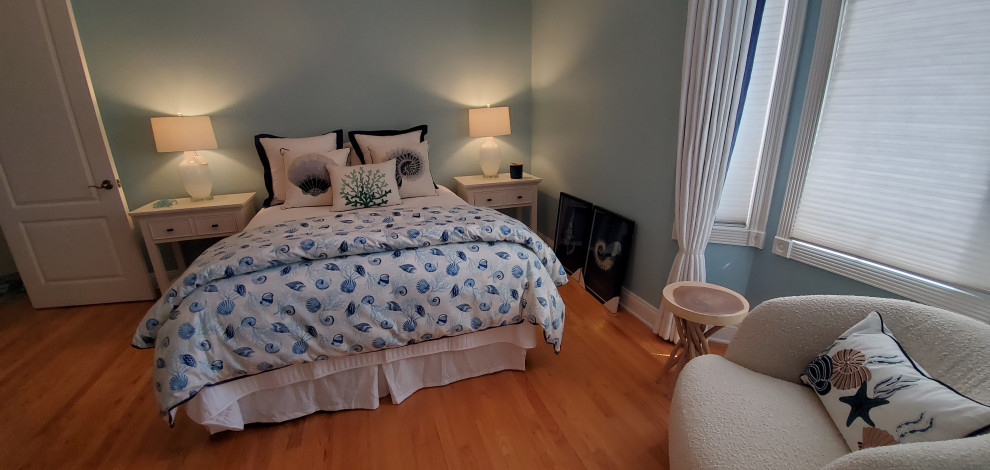 Modelo de habitación de invitados costera de tamaño medio con paredes azules, suelo de madera clara y suelo azul