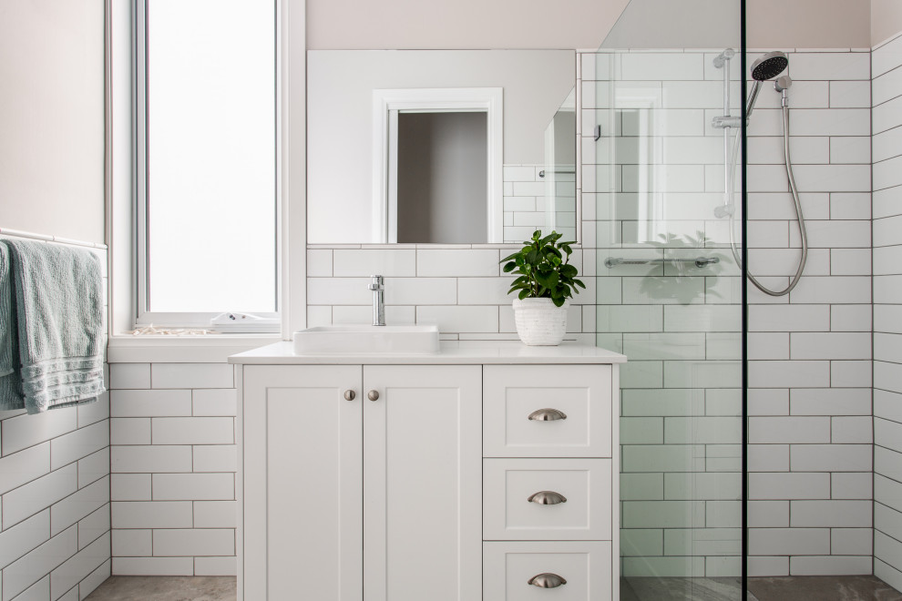 Photo of a transitional 3/4 bathroom in Adelaide with shaker cabinets, white cabinets, a curbless shower, subway tile, a drop-in sink, grey floor, a hinged shower door and white benchtops.