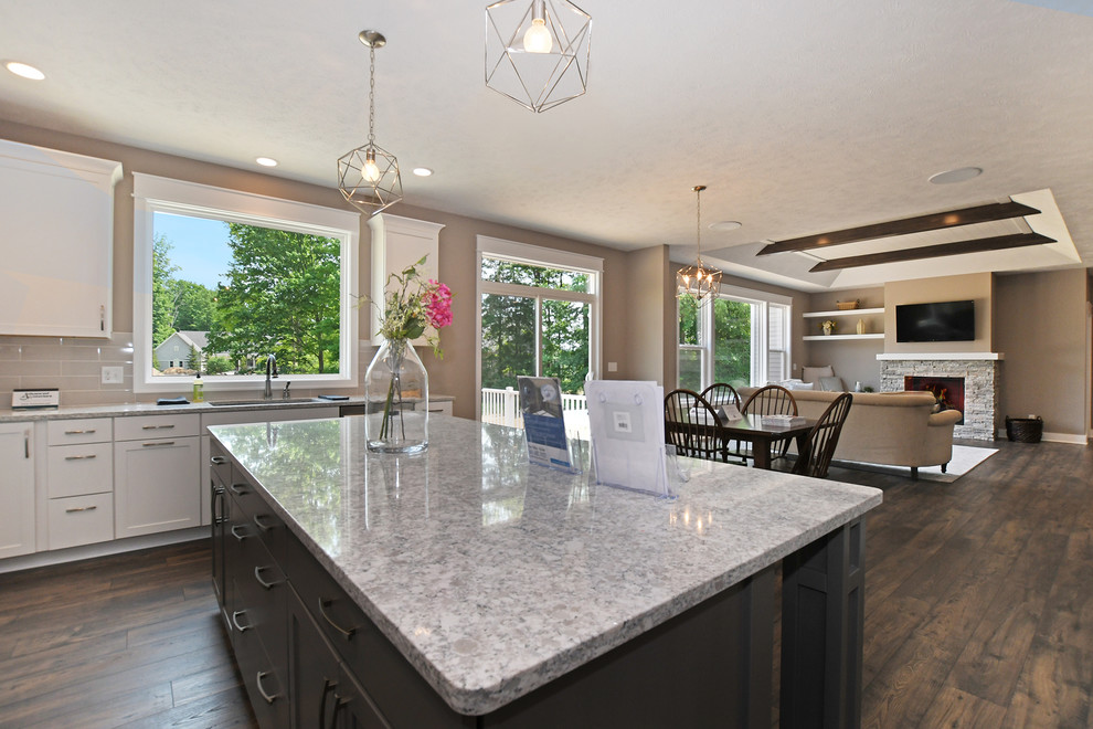 Example of a large galley vinyl floor and brown floor eat-in kitchen design in Grand Rapids with an undermount sink, shaker cabinets, white cabinets, quartzite countertops, beige backsplash, subway tile backsplash, stainless steel appliances, an island and gray countertops