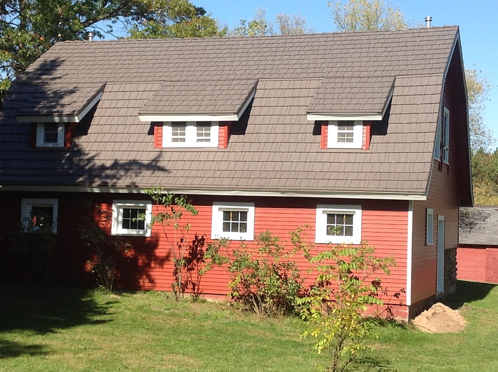 This is an example of a mid-sized country two-storey red exterior in Minneapolis with metal siding and a gambrel roof.