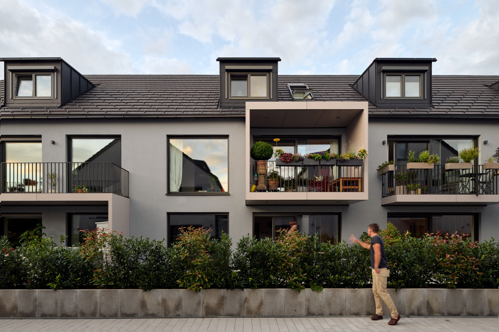 На фото: большой, трехэтажный, разноцветный дуплекс в современном стиле с облицовкой из бетона, двускатной крышей и черной крышей