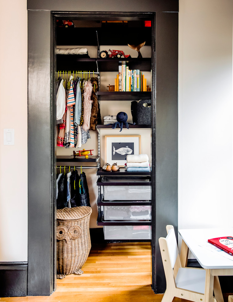 Inspiration for a small traditional gender-neutral built-in wardrobe in San Francisco with black cabinets, light hardwood floors and brown floor.