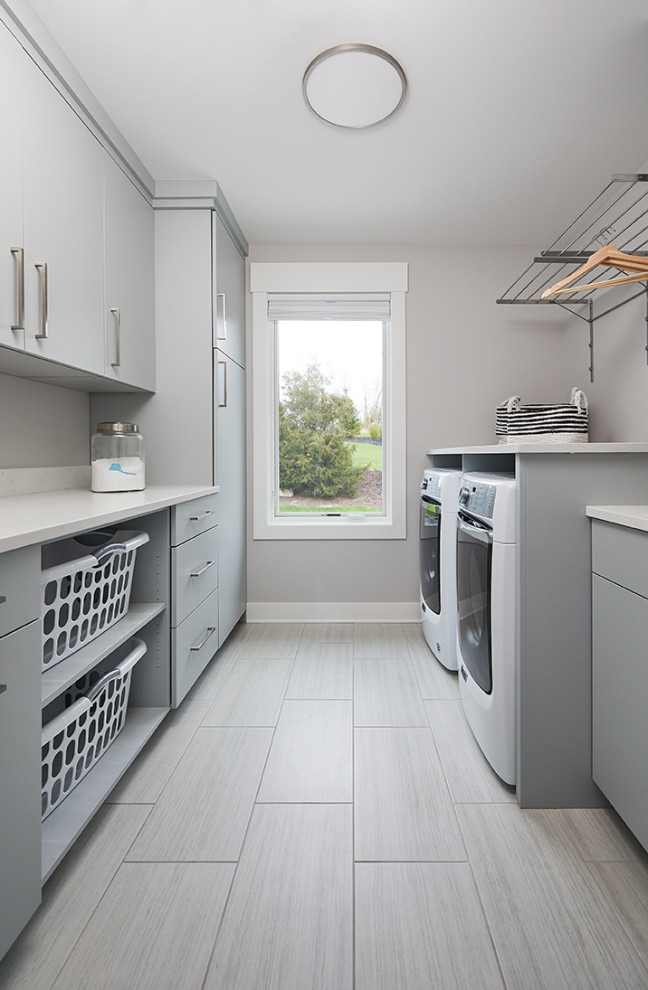 Inspiration for a transitional galley dedicated laundry room in Grand Rapids with flat-panel cabinets, grey cabinets, quartzite benchtops, porcelain floors, a side-by-side washer and dryer, grey floor and white benchtop.