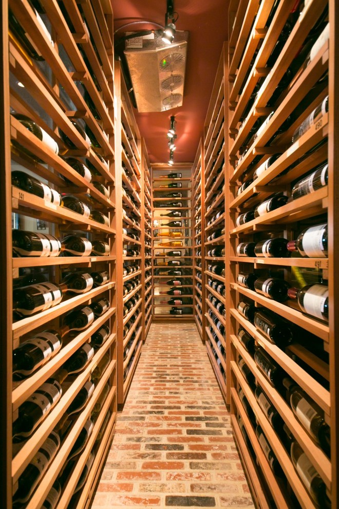 This is an example of a modern wine cellar in New York with brick floors and display racks.
