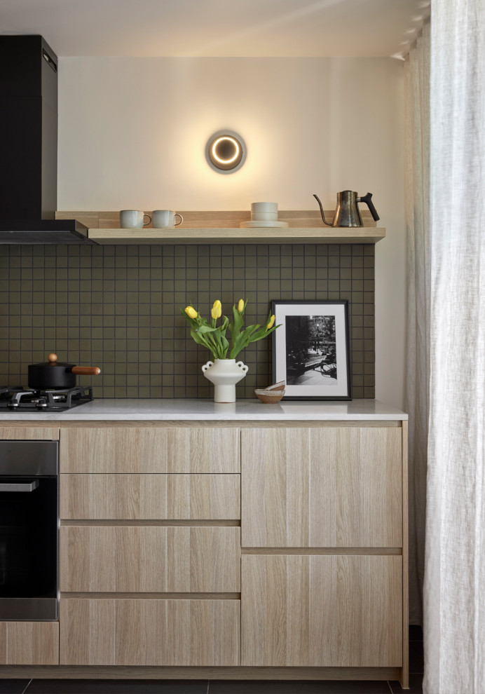This is an example of a small scandinavian single-wall open plan kitchen in Melbourne with an undermount sink, flat-panel cabinets, light wood cabinets, quartz benchtops, green splashback, ceramic splashback, black appliances, light hardwood floors, no island, yellow floor and grey benchtop.