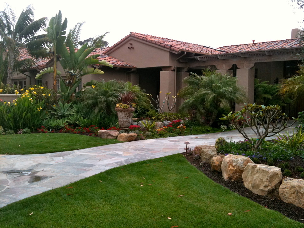 Design ideas for a large mediterranean front yard driveway in San Diego with natural stone pavers.