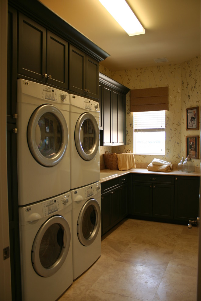 Inspiration for a mid-sized traditional l-shaped dedicated laundry room in Miami with a drop-in sink, shaker cabinets, dark wood cabinets, travertine floors, a stacked washer and dryer and beige walls.