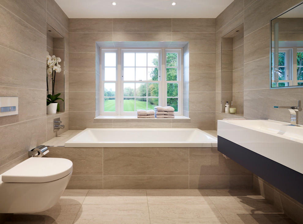 Photo of a large transitional master bathroom in Surrey with flat-panel cabinets, dark wood cabinets, an alcove tub, a wall-mount toilet, gray tile, porcelain tile, grey walls, porcelain floors and a wall-mount sink.