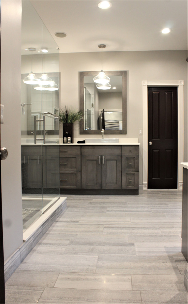 Photo of a large transitional master bathroom in Detroit with recessed-panel cabinets, medium wood cabinets, an open shower, a two-piece toilet, black and white tile, ceramic tile, grey walls, porcelain floors, a vessel sink, engineered quartz benchtops, grey floor, a hinged shower door, white benchtops, a shower seat, a double vanity and a freestanding vanity.