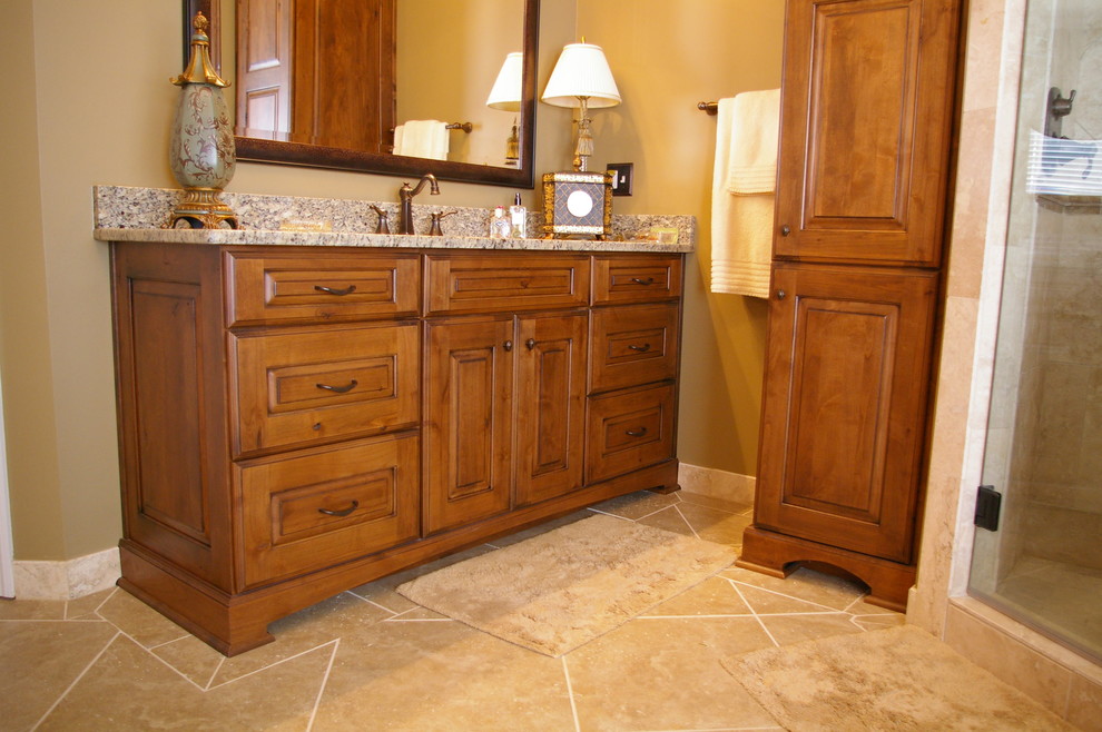 Large mountain style master beige tile and porcelain tile porcelain tile and beige floor drop-in bathtub photo in Atlanta with an undermount sink, flat-panel cabinets, medium tone wood cabinets, granite countertops, a two-piece toilet, beige walls and a hinged shower door