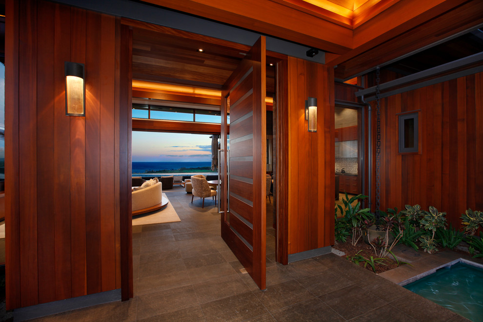 Large tropical front door in Hawaii with a pivot front door and a dark wood front door.