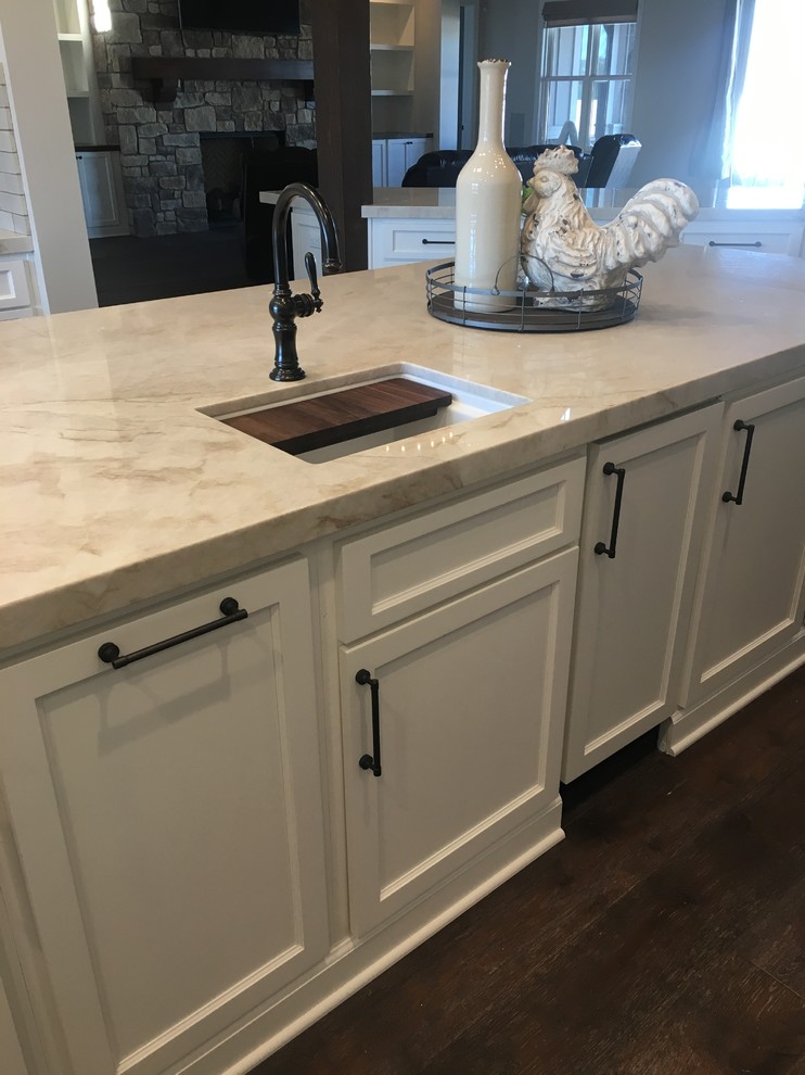 Design ideas for a large country open plan kitchen in Other with a farmhouse sink, shaker cabinets, white cabinets, quartzite benchtops, beige splashback, brick splashback, stainless steel appliances, dark hardwood floors, multiple islands and brown floor.