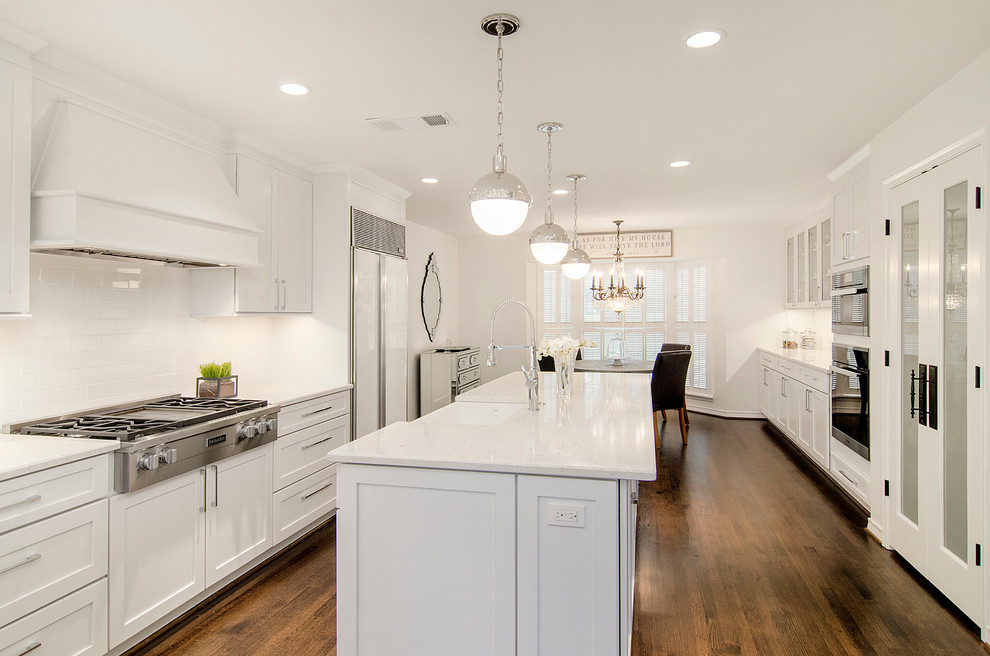 Inspiration for a mid-sized transitional u-shaped medium tone wood floor kitchen pantry remodel in Dallas with a farmhouse sink, open cabinets, white cabinets, solid surface countertops, white backsplash, subway tile backsplash, stainless steel appliances and an island