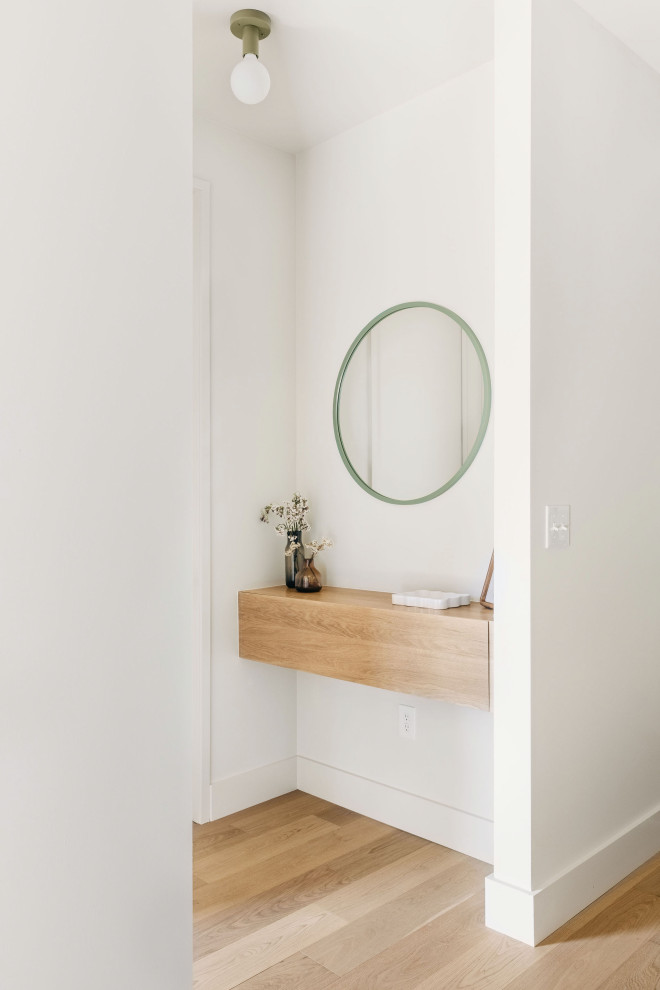 Example of a small danish light wood floor and beige floor hallway design with white walls
