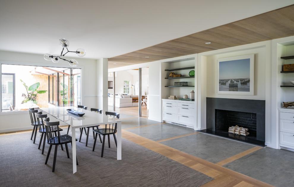 Expansive contemporary separate dining room in Boston with white walls, medium hardwood floors, a standard fireplace, a concrete fireplace surround and brown floor.