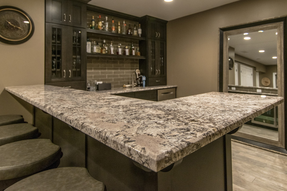 Design ideas for a large modern l-shaped seated home bar in Chicago with an undermount sink, marble benchtops, grey splashback, stone tile splashback, laminate floors, beige floor and grey benchtop.