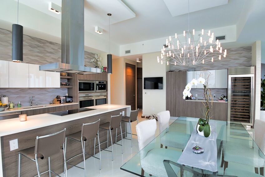 This is an example of a contemporary eat-in kitchen in Miami with a single-bowl sink, flat-panel cabinets, quartzite benchtops, beige splashback, stainless steel appliances, with island and white floor.