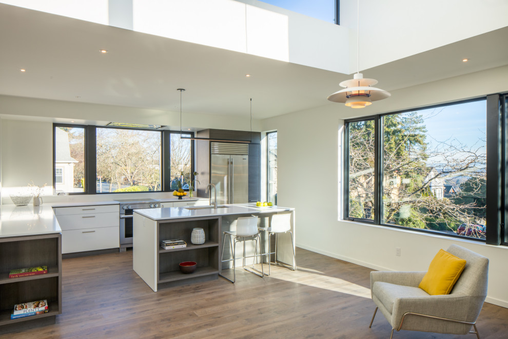 This is an example of a mid-sized contemporary l-shaped open plan kitchen in Seattle with flat-panel cabinets, white cabinets and white benchtop.