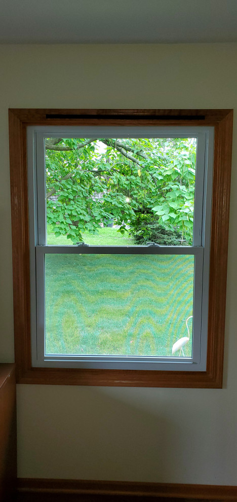 White vinyl replacement window with existing golden oak trim