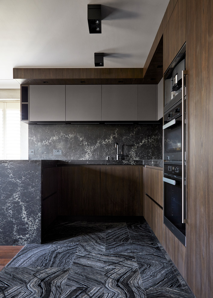 This is an example of a mid-sized modern u-shaped open plan kitchen in London with an integrated sink, flat-panel cabinets, dark wood cabinets, marble benchtops, black splashback, stone slab splashback, black appliances, marble floors, a peninsula, black floor and black benchtop.