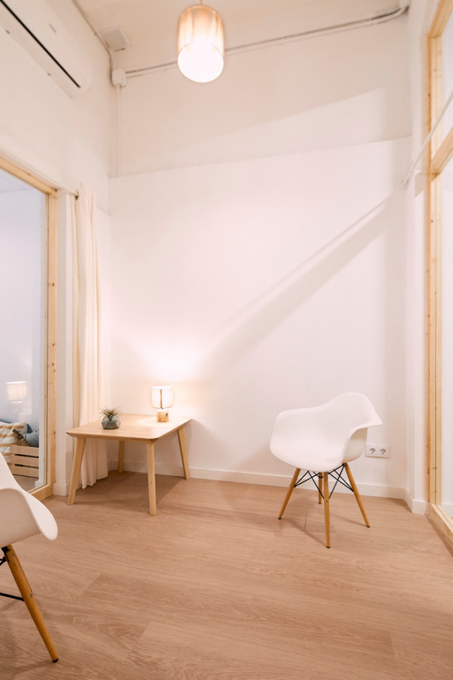 Imagen de sala de estar cerrada y abovedada escandinava pequeña con paredes blancas, suelo de madera clara, suelo beige y madera
