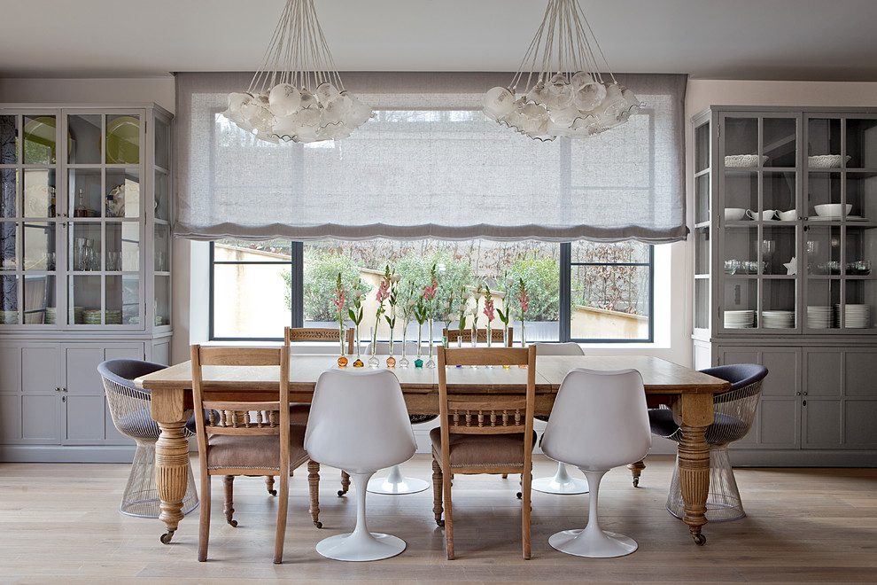 Inspiration for a large contemporary dining room in London with white walls, light hardwood floors and no fireplace.