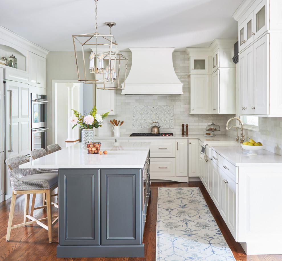 Bild på ett mellanstort vintage vit vitt kök, med en rustik diskho, skåp i shakerstil, vita skåp, bänkskiva i kvartsit, vitt stänkskydd, stänkskydd i tunnelbanekakel, vita vitvaror, mellanmörkt trägolv, en köksö och brunt golv
