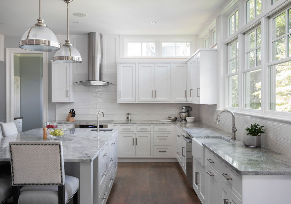 Open concept kitchen - transitional l-shaped dark wood floor and brown floor open concept kitchen idea in Boston with a farmhouse sink, white cabinets, marble countertops, white backsplash, ceramic backsplash, stainless steel appliances, an island and shaker cabinets