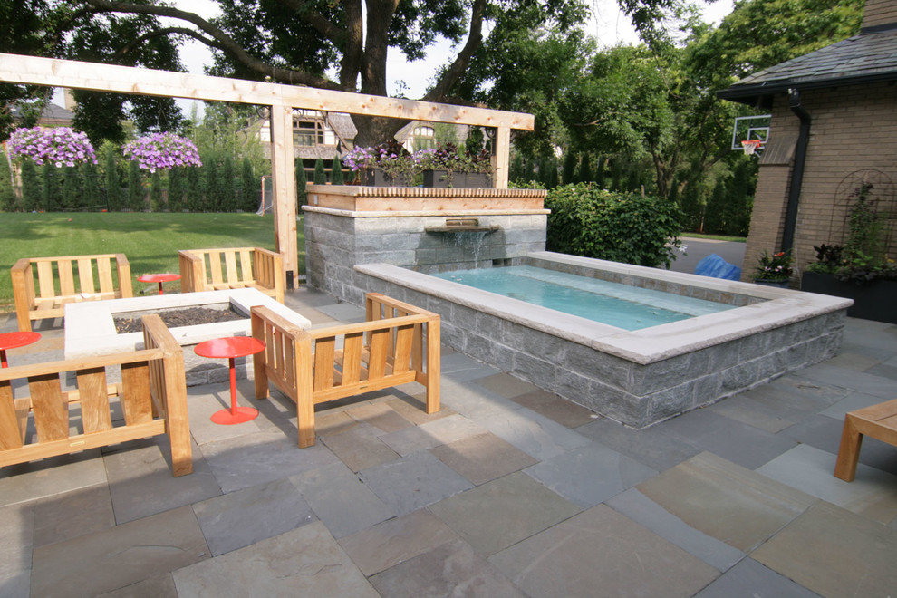 This is an example of a small contemporary backyard rectangular aboveground pool in Minneapolis with a hot tub and natural stone pavers.