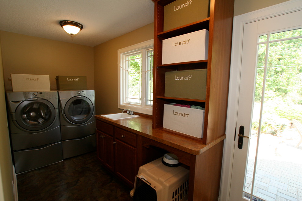 Design ideas for a mid-sized transitional l-shaped utility room in Minneapolis with a drop-in sink, shaker cabinets, medium wood cabinets, laminate benchtops, beige walls, linoleum floors and a side-by-side washer and dryer.