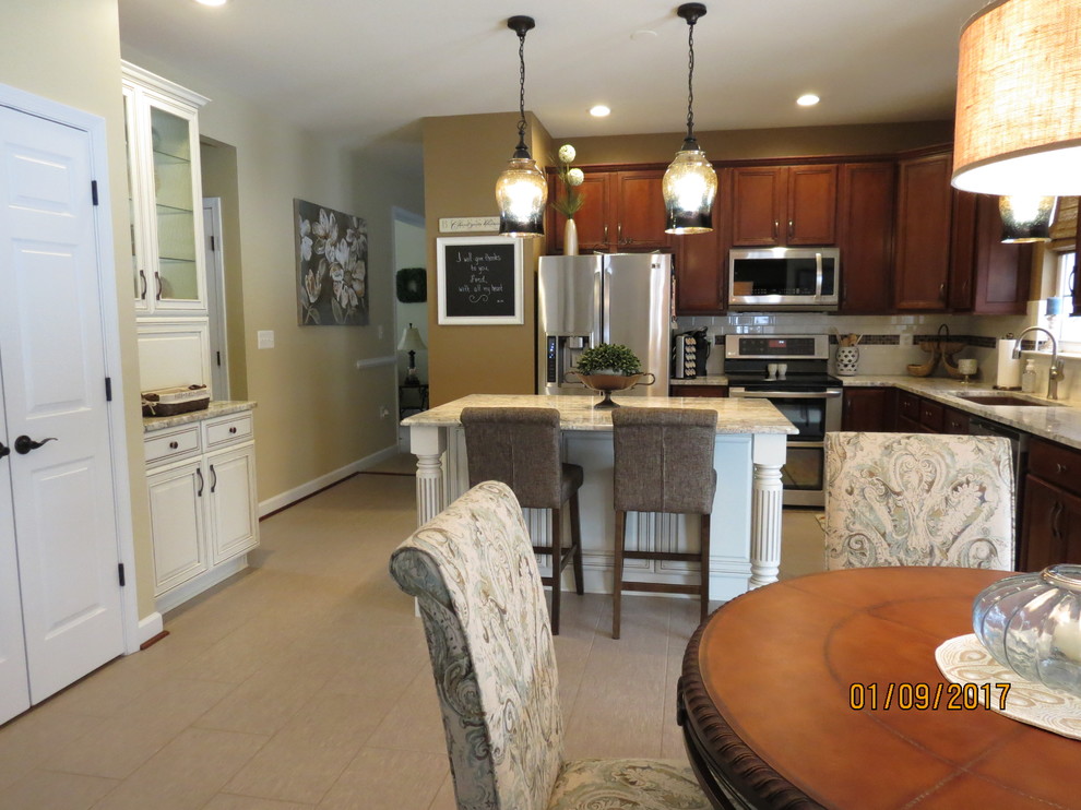 Example of a mid-sized transitional l-shaped ceramic tile eat-in kitchen design with an undermount sink, raised-panel cabinets, distressed cabinets, granite countertops, white backsplash, porcelain backsplash, stainless steel appliances and an island