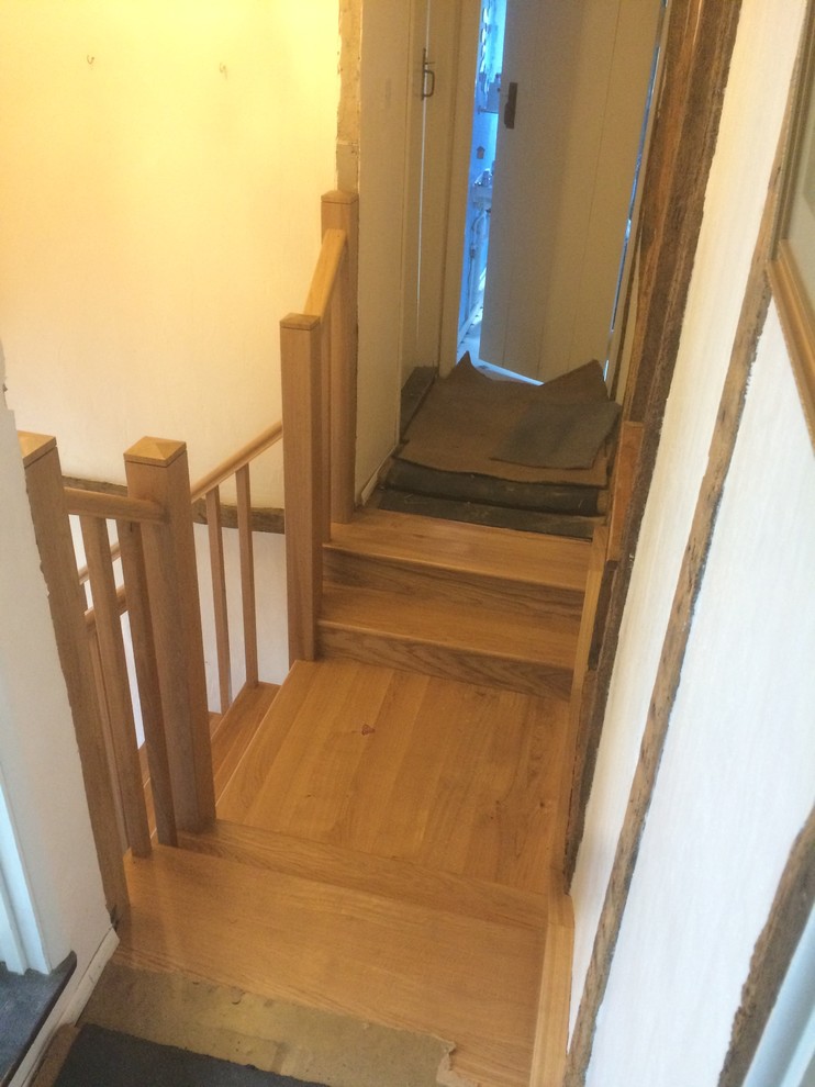 This is an example of a large modern wood straight staircase in Essex with wood risers and wood railing.