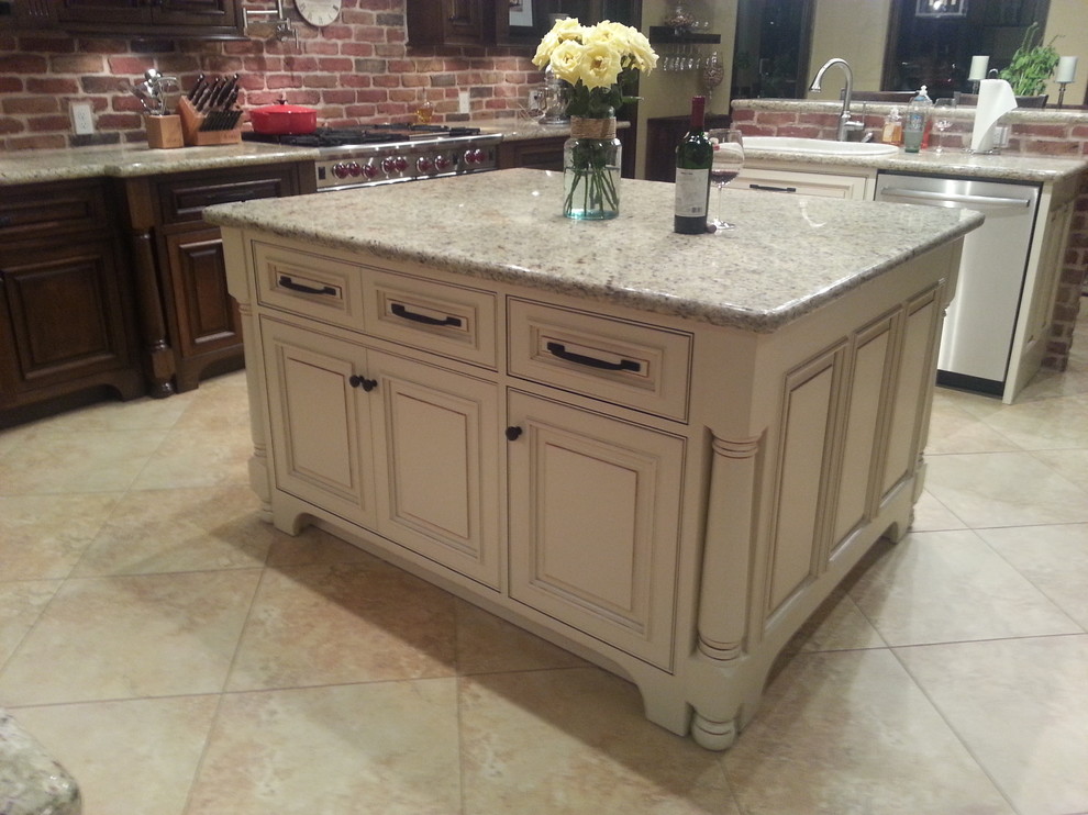 Example of a large mountain style u-shaped porcelain tile eat-in kitchen design in Houston with an undermount sink, raised-panel cabinets, dark wood cabinets, granite countertops, red backsplash, brick backsplash, stainless steel appliances and two islands