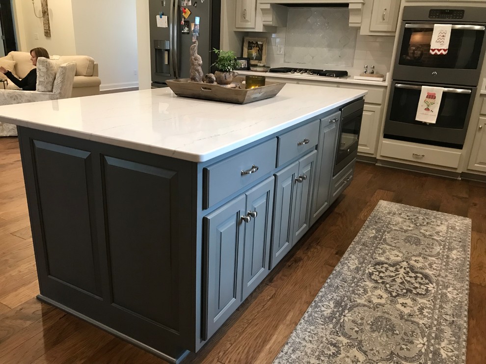 Inspiration for a large transitional l-shaped dark wood floor and brown floor open concept kitchen remodel with a double-bowl sink, raised-panel cabinets, gray cabinets, white backsplash, subway tile backsplash, stainless steel appliances, an island and white countertops