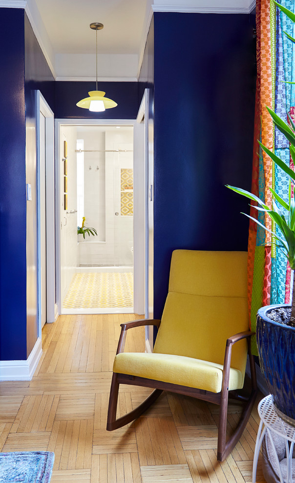 This is an example of a mid-sized eclectic hallway in New York with blue walls and light hardwood floors.