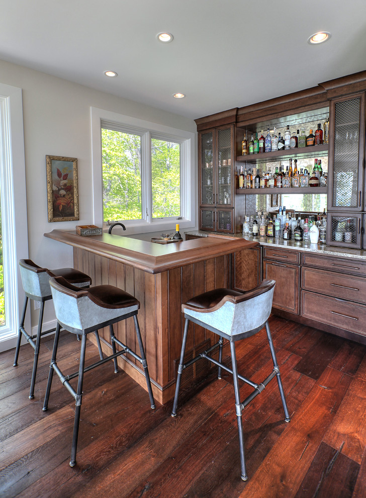 Large transitional seated home bar in Other with recessed-panel cabinets, dark wood cabinets, dark hardwood floors, wood benchtops, mirror splashback and brown benchtop.