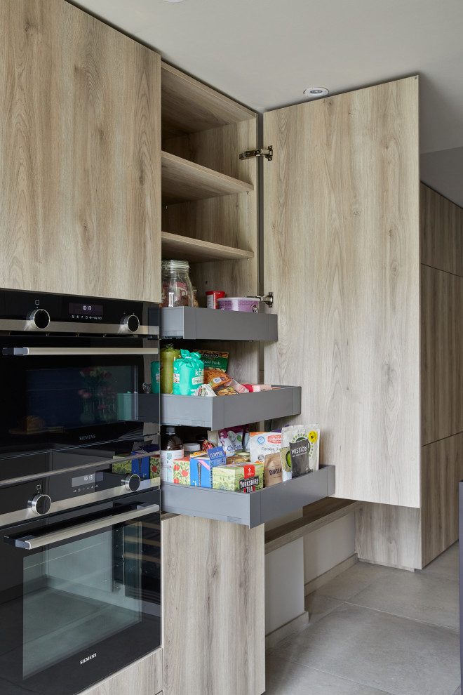 Photo of a mid-sized contemporary galley separate kitchen in London with flat-panel cabinets, quartz benchtops, brown splashback, engineered quartz splashback, a peninsula and brown benchtop.