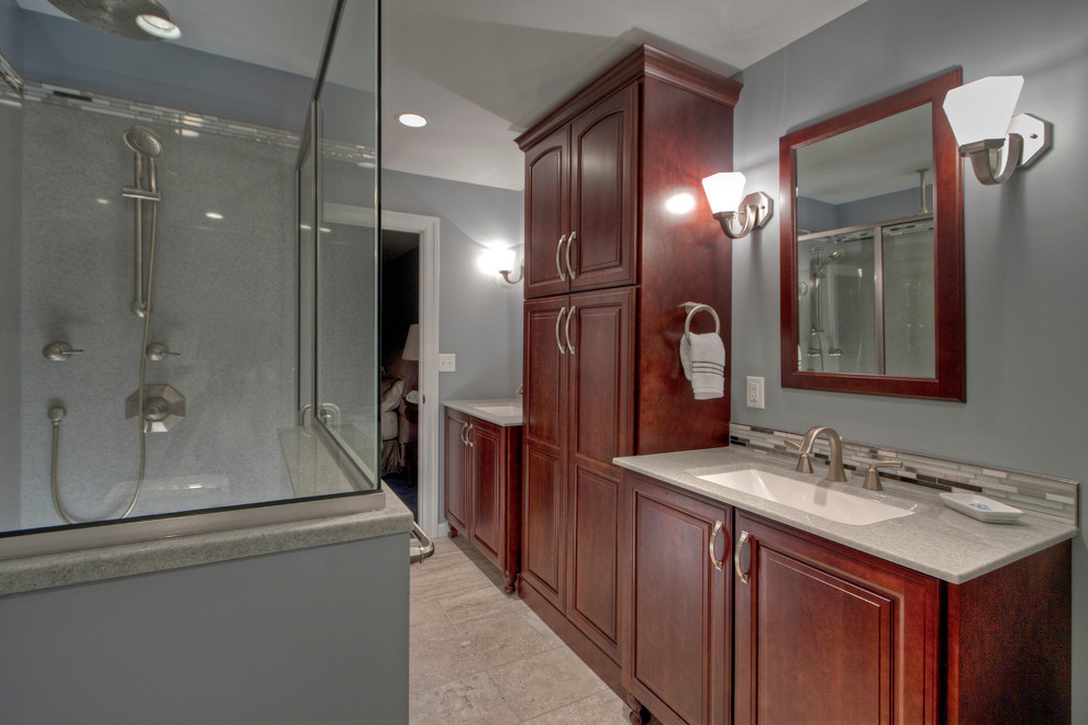 Large contemporary master bathroom in St Louis with an integrated sink, recessed-panel cabinets, medium wood cabinets, onyx benchtops, an alcove tub, a corner shower, a one-piece toilet, multi-coloured tile, glass tile, grey walls and ceramic floors.