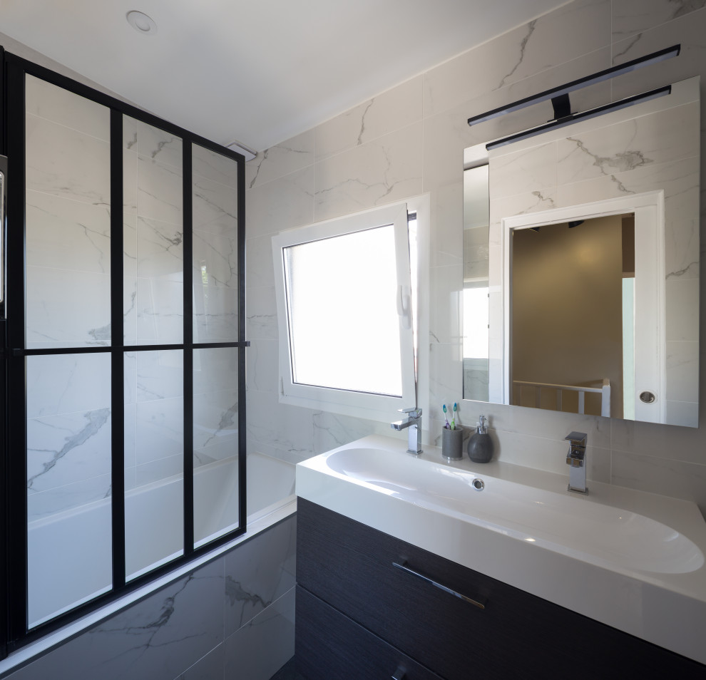 Example of a small trendy master white tile and marble tile slate floor, black floor and single-sink drop-in bathtub design in Paris with flat-panel cabinets, dark wood cabinets, a wall-mount toilet, white walls, a console sink, solid surface countertops, white countertops, a niche and a floating vanity