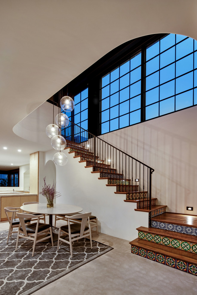 Design ideas for a mid-sized mediterranean wood l-shaped staircase in Los Angeles with tile risers and metal railing.