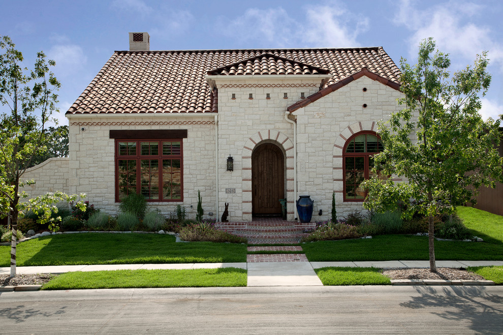 This is an example of a mediterranean one-storey white exterior in Dallas with stone veneer.