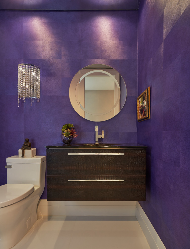 Inspiration for a mid-sized contemporary powder room in Miami with flat-panel cabinets, dark wood cabinets, a one-piece toilet, purple walls, an integrated sink and white floor.