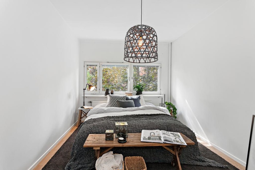Mid-sized scandinavian master bedroom in Stockholm with white walls and light hardwood floors.