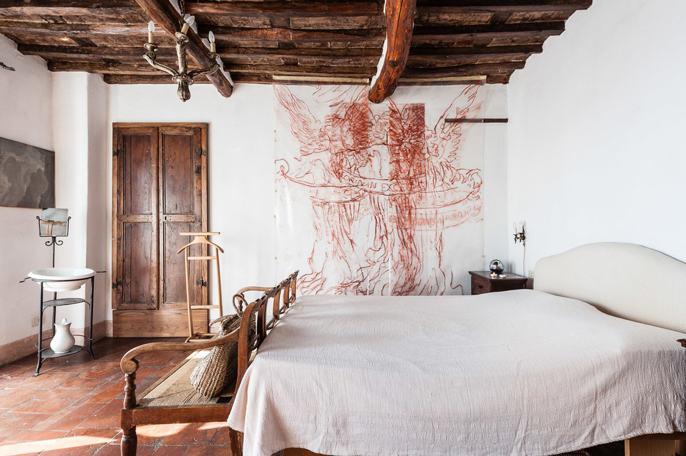 This is an example of a country bedroom in Other with white walls, terra-cotta floors and red floor.