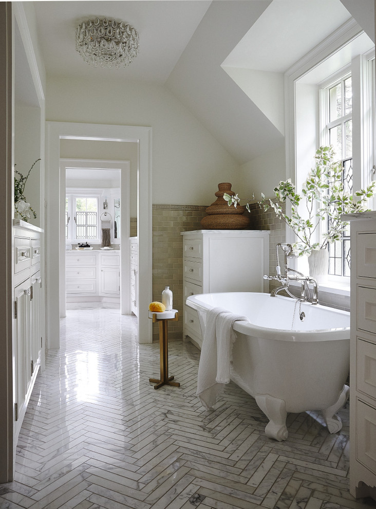 Cette photo montre une salle de bain chic avec une baignoire indépendante, un sol en carrelage de céramique, un sol gris, un placard avec porte à panneau encastré, des portes de placard blanches, un carrelage beige, des carreaux de céramique, un mur blanc, un plan de toilette en marbre, un plan de toilette blanc, meuble double vasque et meuble-lavabo encastré.