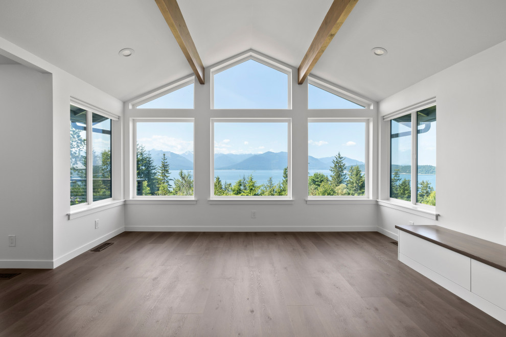 Inspiration for a large transitional single-wall vinyl floor, brown floor and vaulted ceiling open concept kitchen remodel in Seattle with an undermount sink, shaker cabinets, white cabinets, quartz countertops, white backsplash, quartz backsplash, stainless steel appliances, an island and white countertops