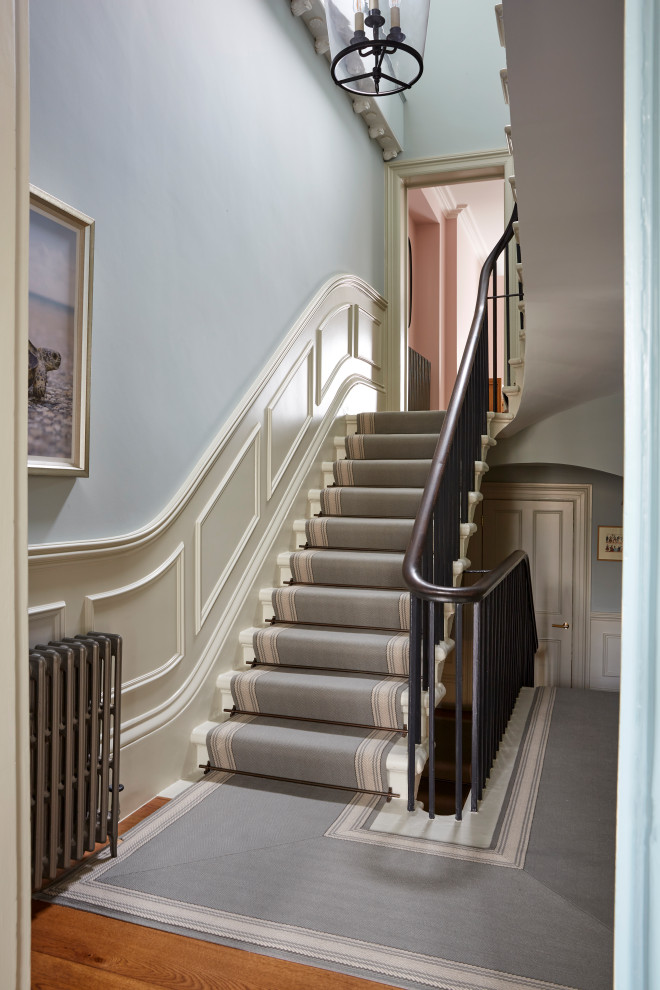 На фото: прямая лестница в классическом стиле с деревянными перилами и панелями на стенах с